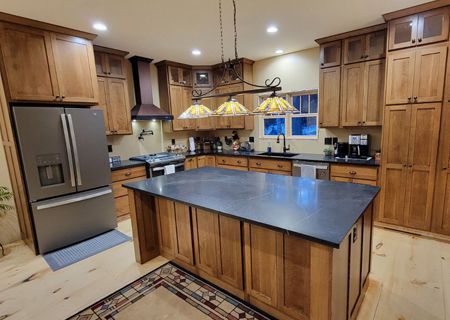 A kitchen with wooden cabinets , granite counter tops , stainless steel appliances and a large island.