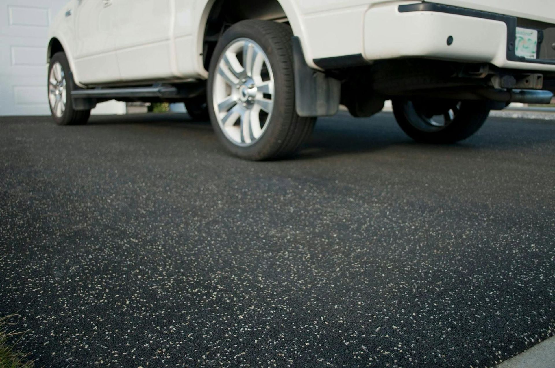 A white truck is parked on a black asphalt driveway