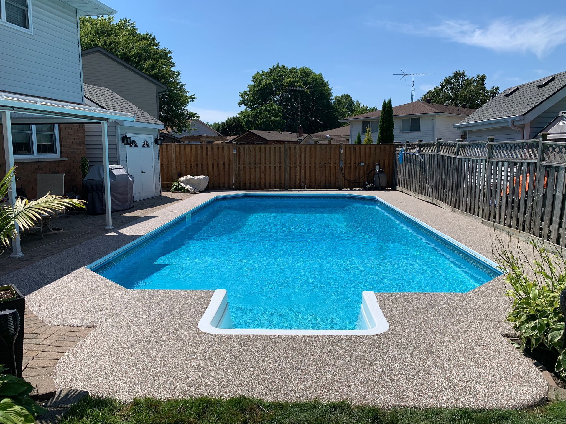 There is a large swimming pool in the backyard of a house.