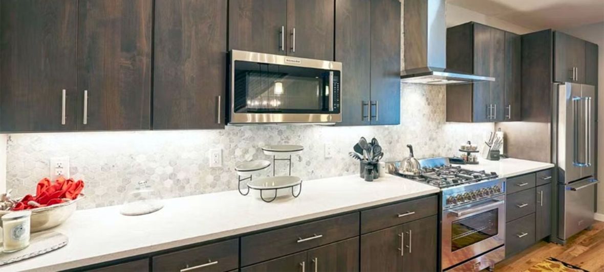 Modern kitchen with dark wood cabinets, white countertops, and stainless steel appliances