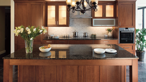 Modern kitchen with dark wood cabinets, granite island, chandelier, and flowers on the counter