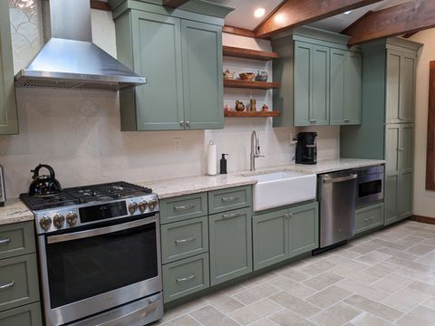 Modern kitchen with sage green cabinets, stainless steel appliances, white countertops, and tiled floor