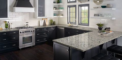 Modern kitchen with dark cabinets, granite island, stainless steel appliances, and large windows