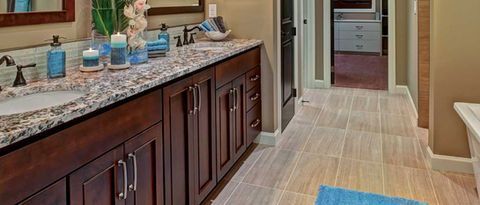 Bathroom vanity with dark wood cabinets, granite countertop, and a tiled floor leading to a doorway