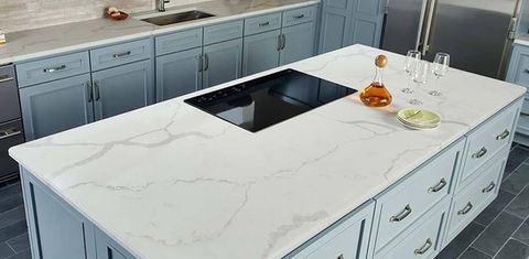Modern kitchen with a white marble island, black sink, and light blue cabinets