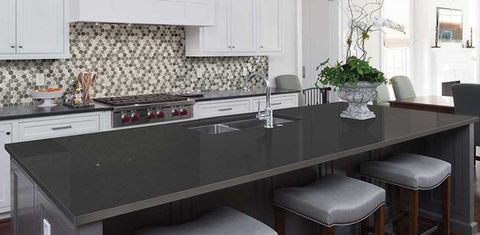 Modern kitchen with dark island countertop, stools, and white cabinets