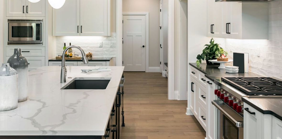 Modern white kitchen with marble island, stainless appliances, and gas range