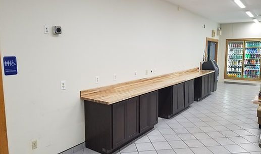 Long hallway with a wooden counter and dark cabinets against a white wall; vending machines in back.