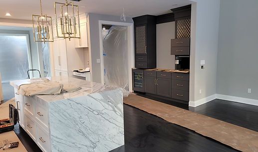 Modern kitchen with marble island, dark cabinets, and pendant lights in a bright open interior.