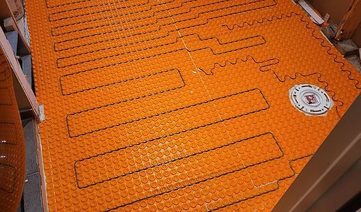 Orange heated floor with rectangular tubing loops and a small gauge on the right side