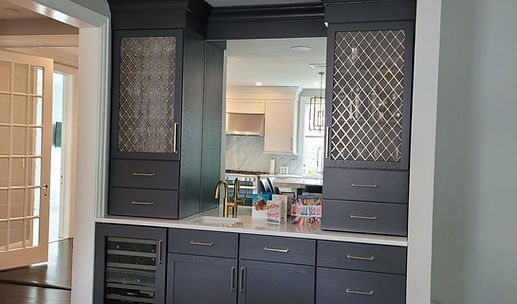Dark gray built-in cabinet with mirror, drawers, and countertop in a bright hallway