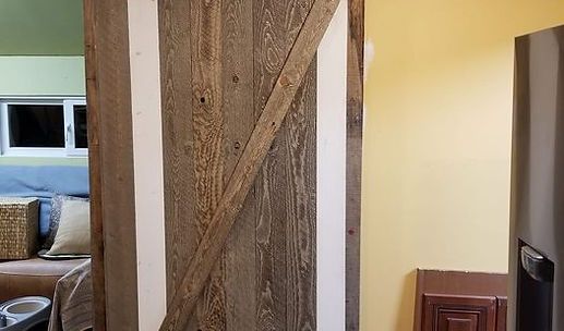 Rustic wooden sliding barn door dividing a yellow hallway from a bedroom
