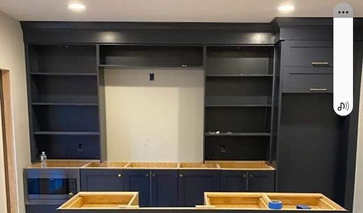 Empty dark wood built-in shelving and cabinets with a white center panel and blue countertop.