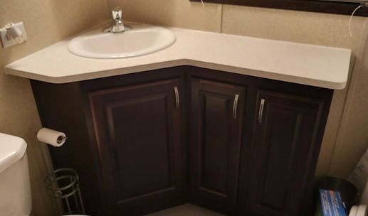 Bathroom vanity with dark wood cabinet, white countertop, and sink under a mirror