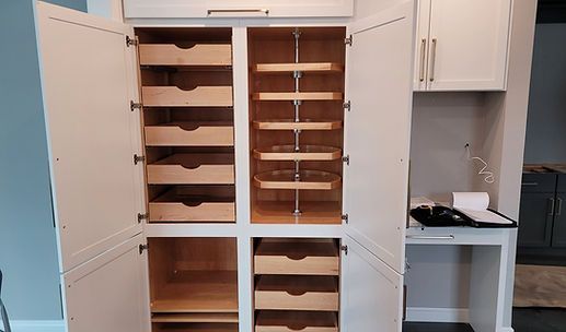Built-in wooden cabinets and shelves in a room, with a desk alcove on the right.