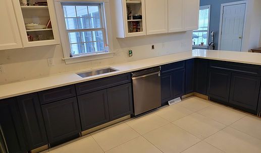 Modern kitchen with dark lower cabinets, white upper cabinets, a sink, and stainless dishwasher