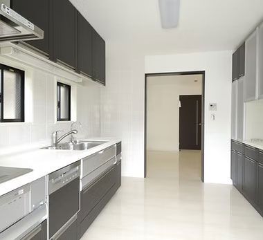 Bright modern kitchen with dark cabinets, white counters, and large windows