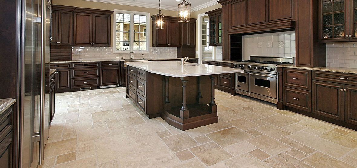 Spacious modern kitchen with dark wood cabinets, central island, stainless appliances, and beige tile floor