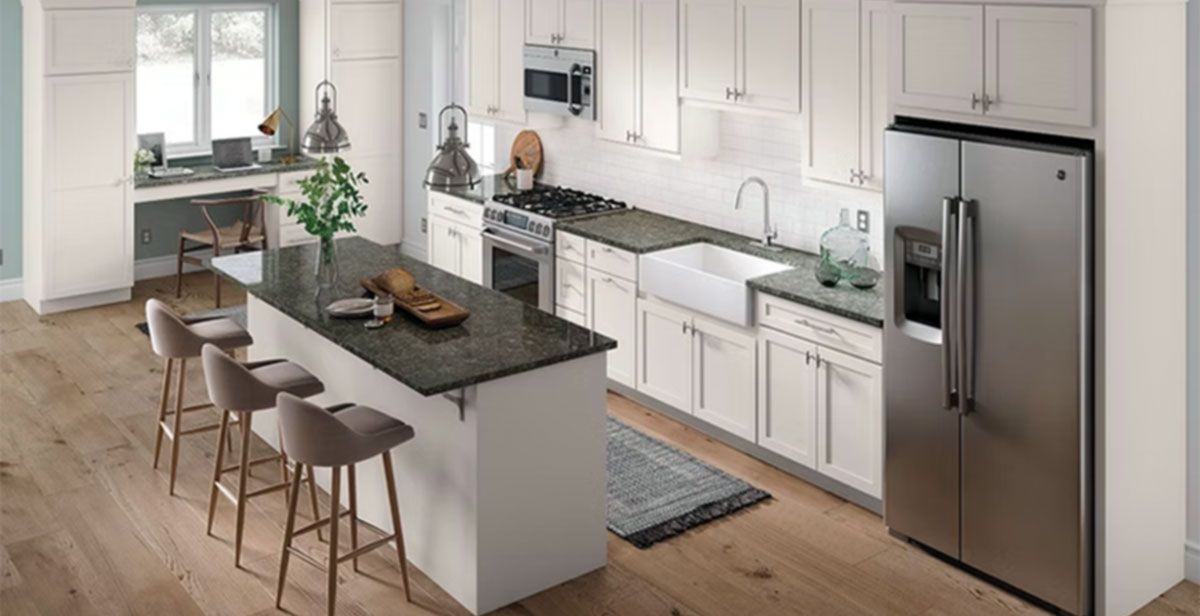 Modern white kitchen with island, bar stools, stainless steel fridge, and a window-lit dining nook