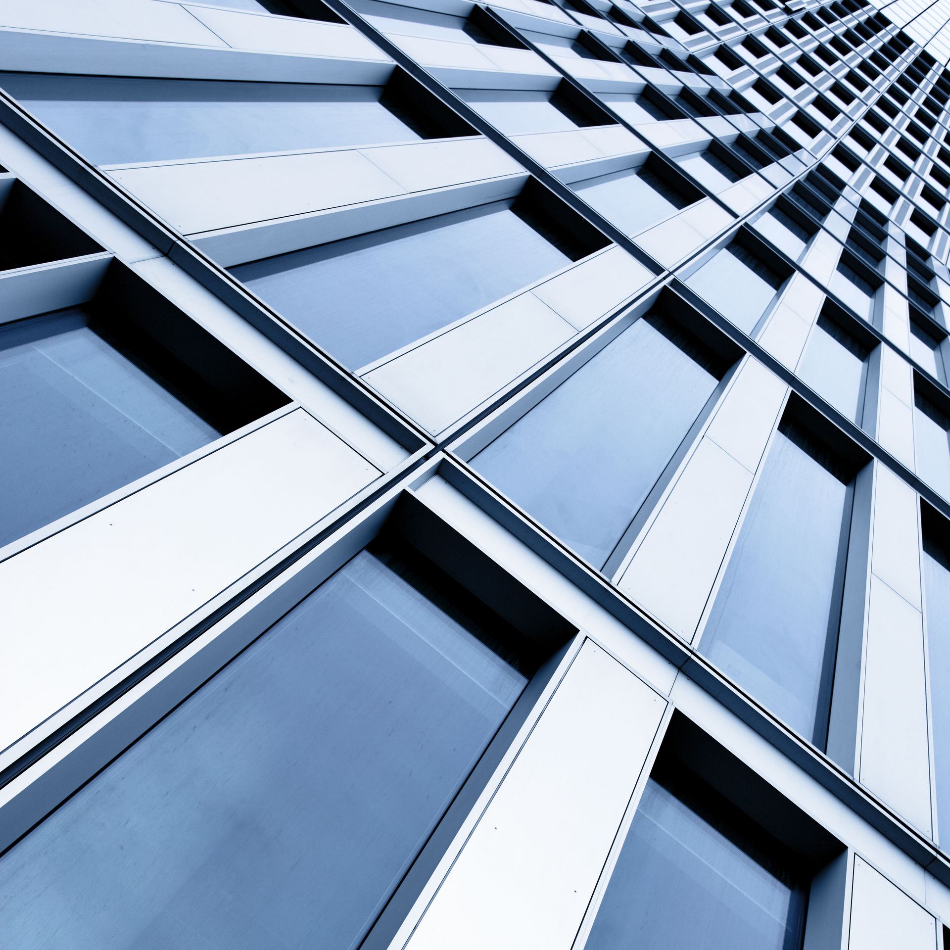 Modern building exterior with a grid of square windows and white frames, angled upward.