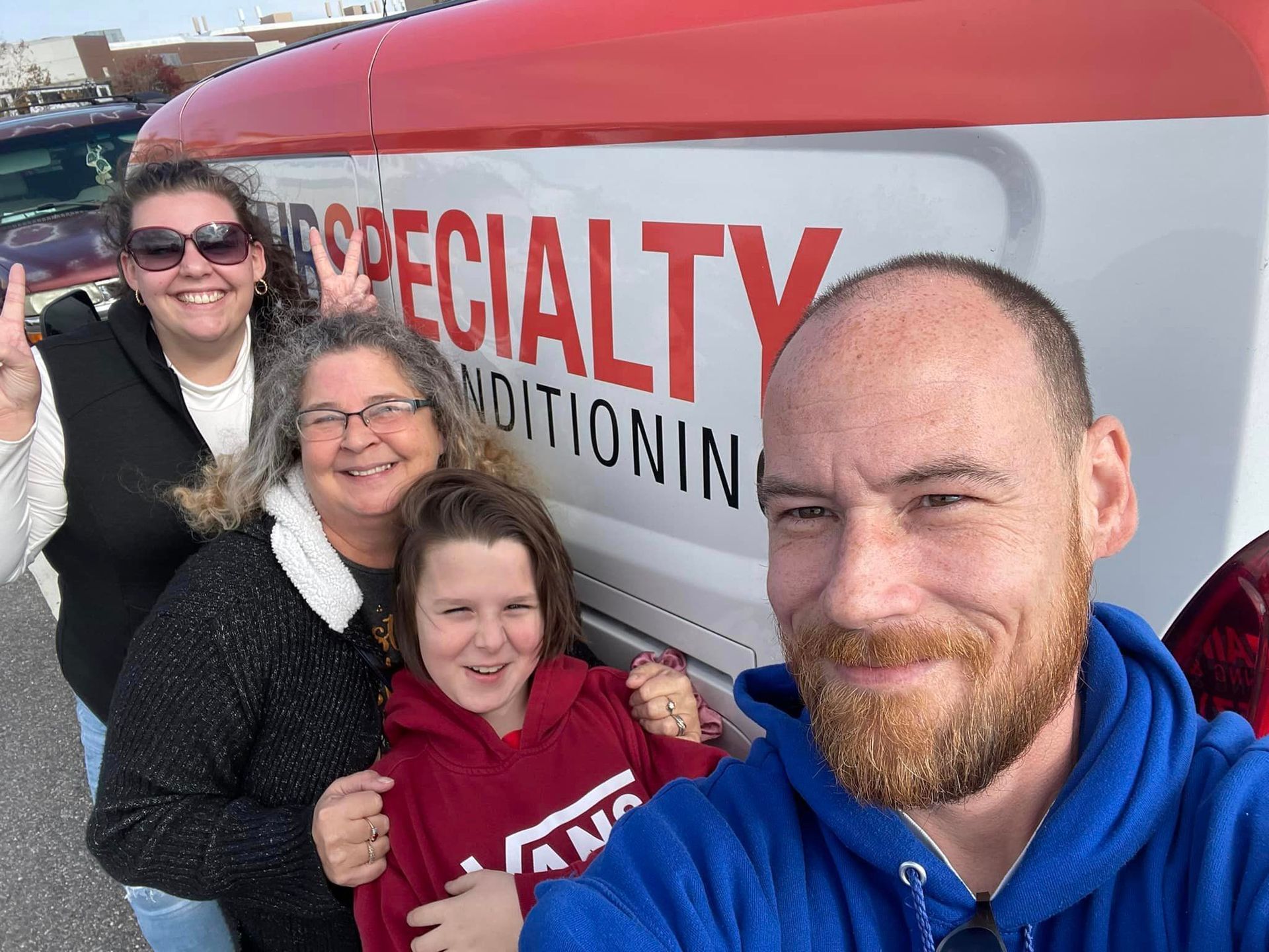 A group of people are posing for a picture in front of a van that says specialty conditioning.