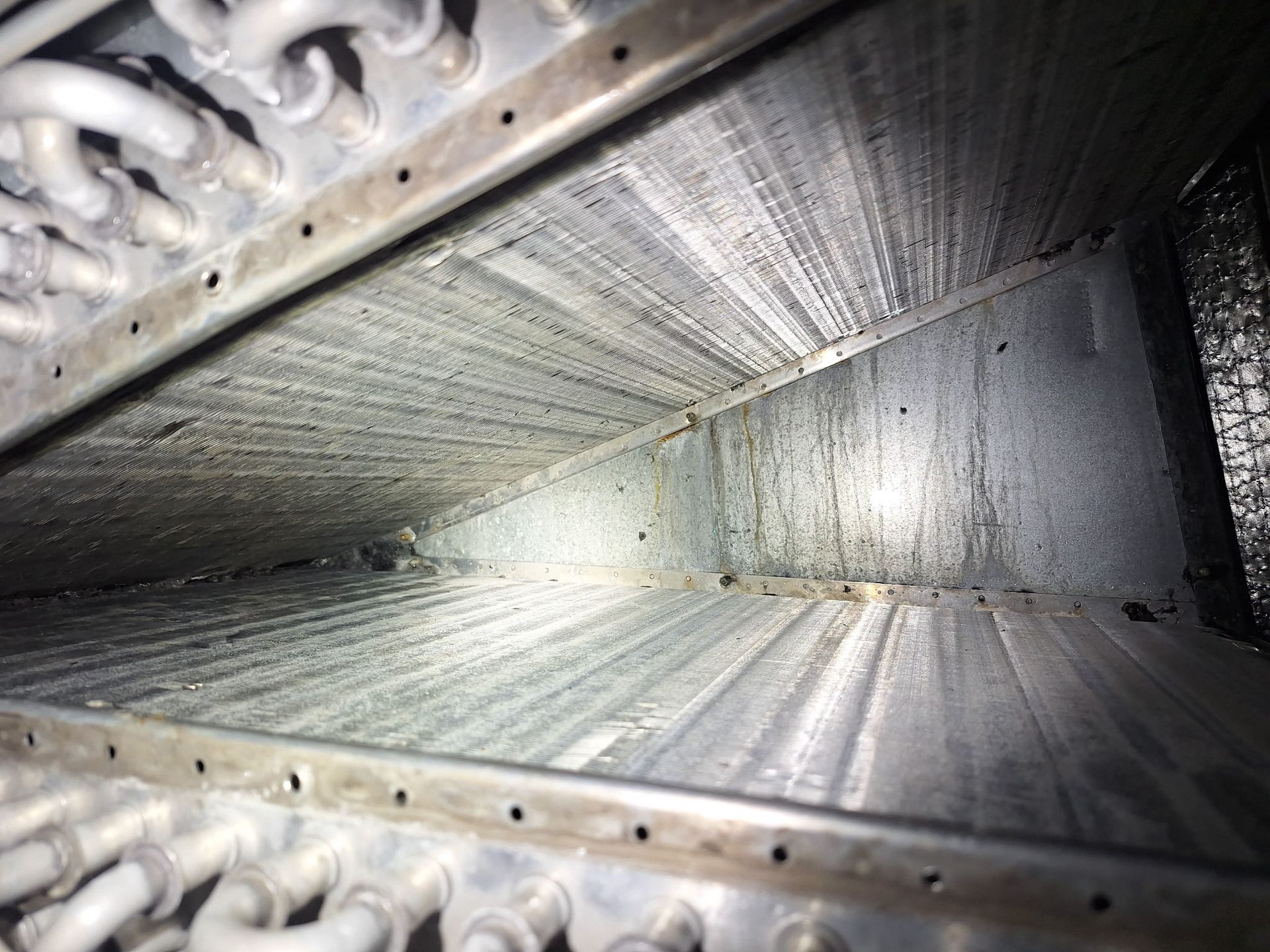 Inside view of a dirty air duct, showing accumulated debris and condensation.