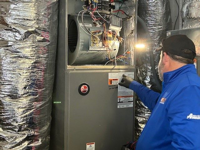 A man in a blue jacket is working on an air conditioner.