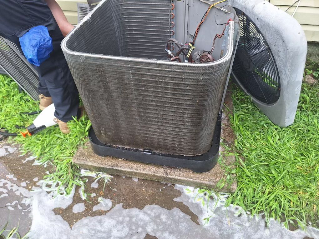 A man is cleaning an air conditioner outside of a house.