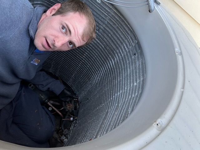 A man is working on an air conditioner inside of a building.