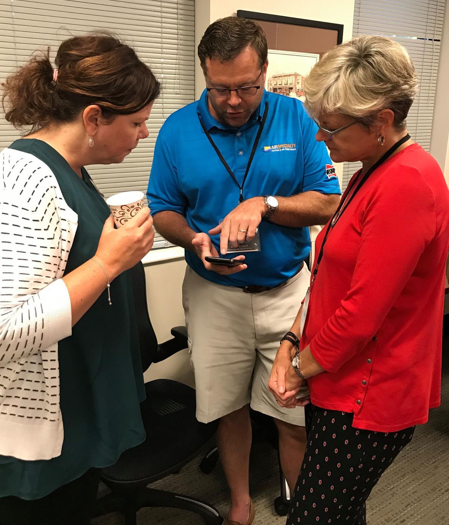 A man in a blue shirt is talking to two women