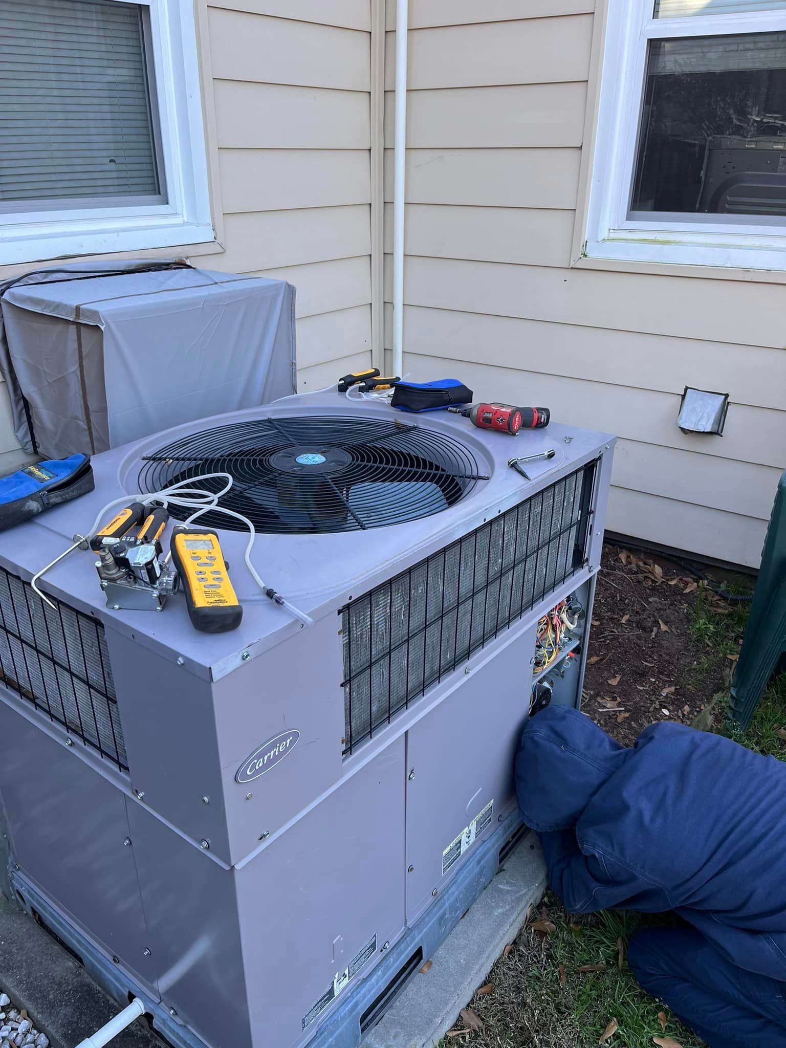 A man is working on an air conditioner outside of a house.