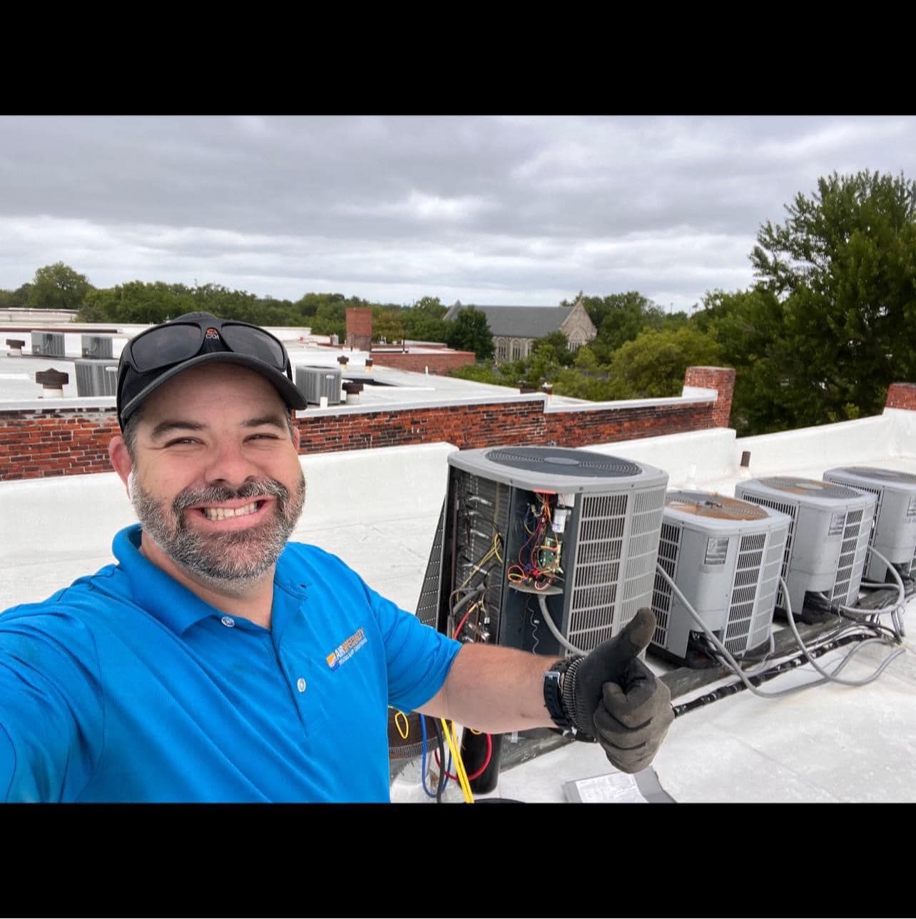 A man in a blue shirt is giving a thumbs up