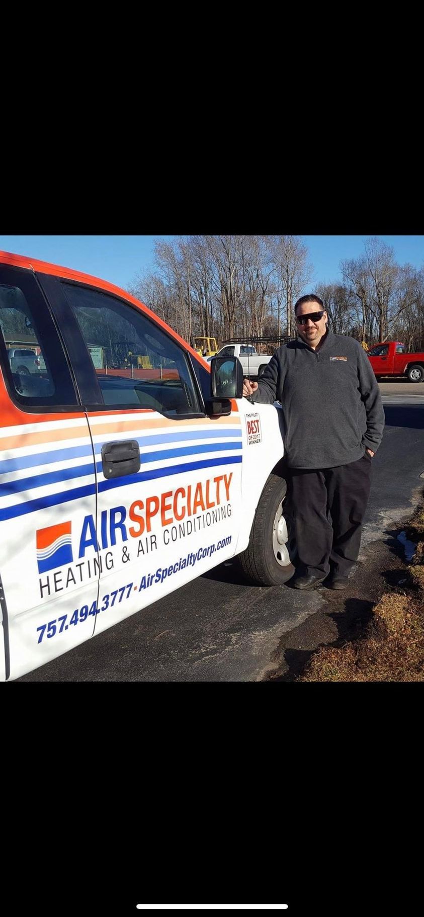 A man is standing in front of an air specialty heating and cooling truck.