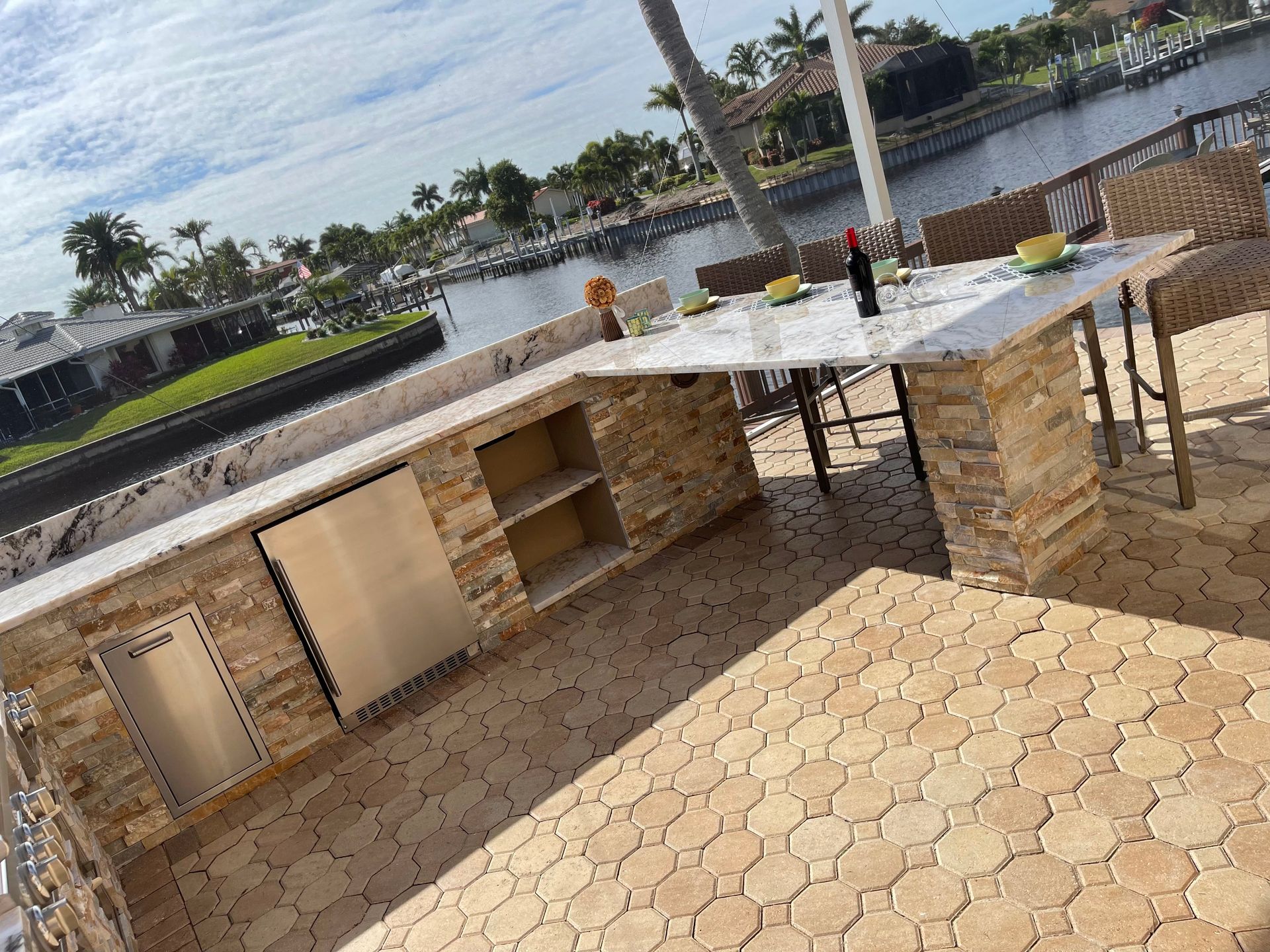 A patio with a table and chairs and a bottle of wine on it.