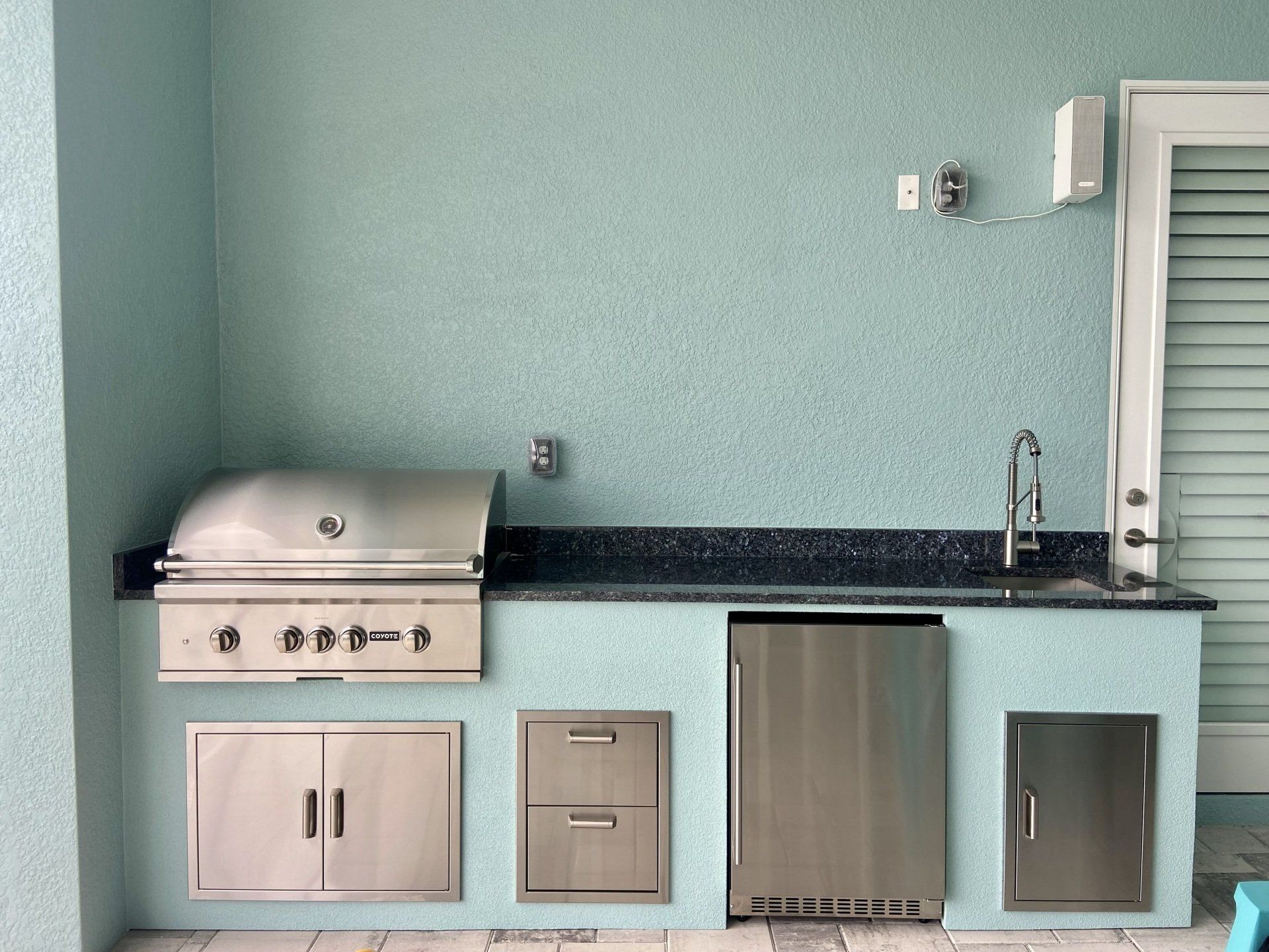 A kitchen with a stainless steel grill and a sink.