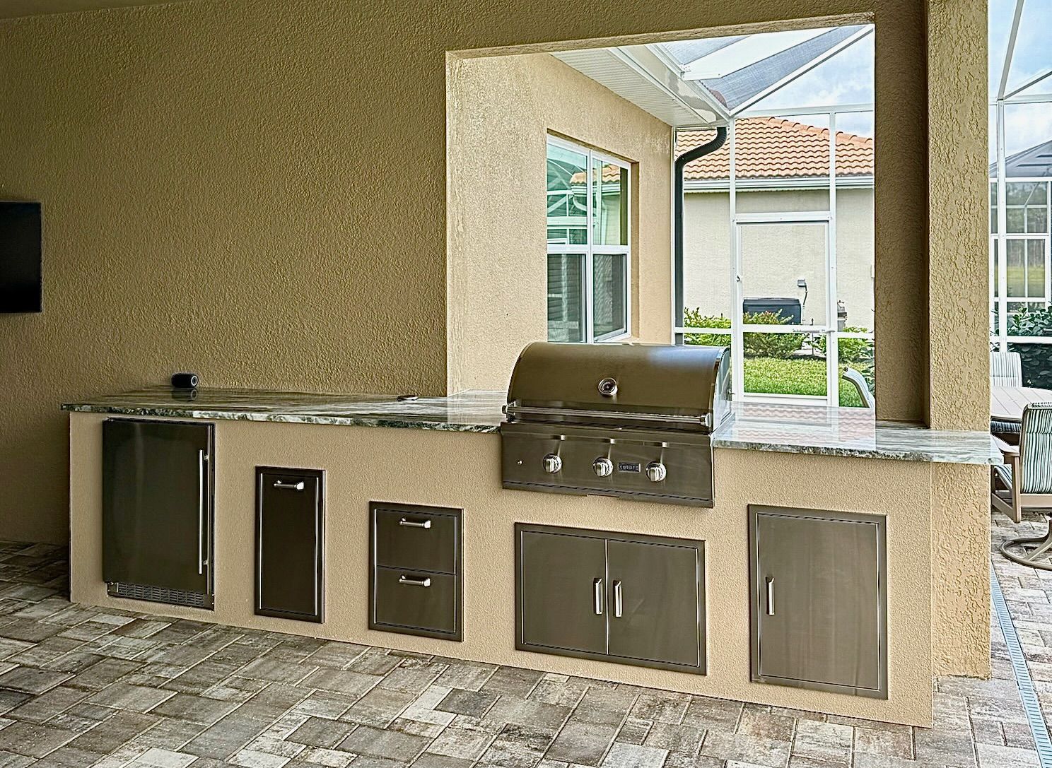 A large outdoor kitchen with a grill and cabinets.