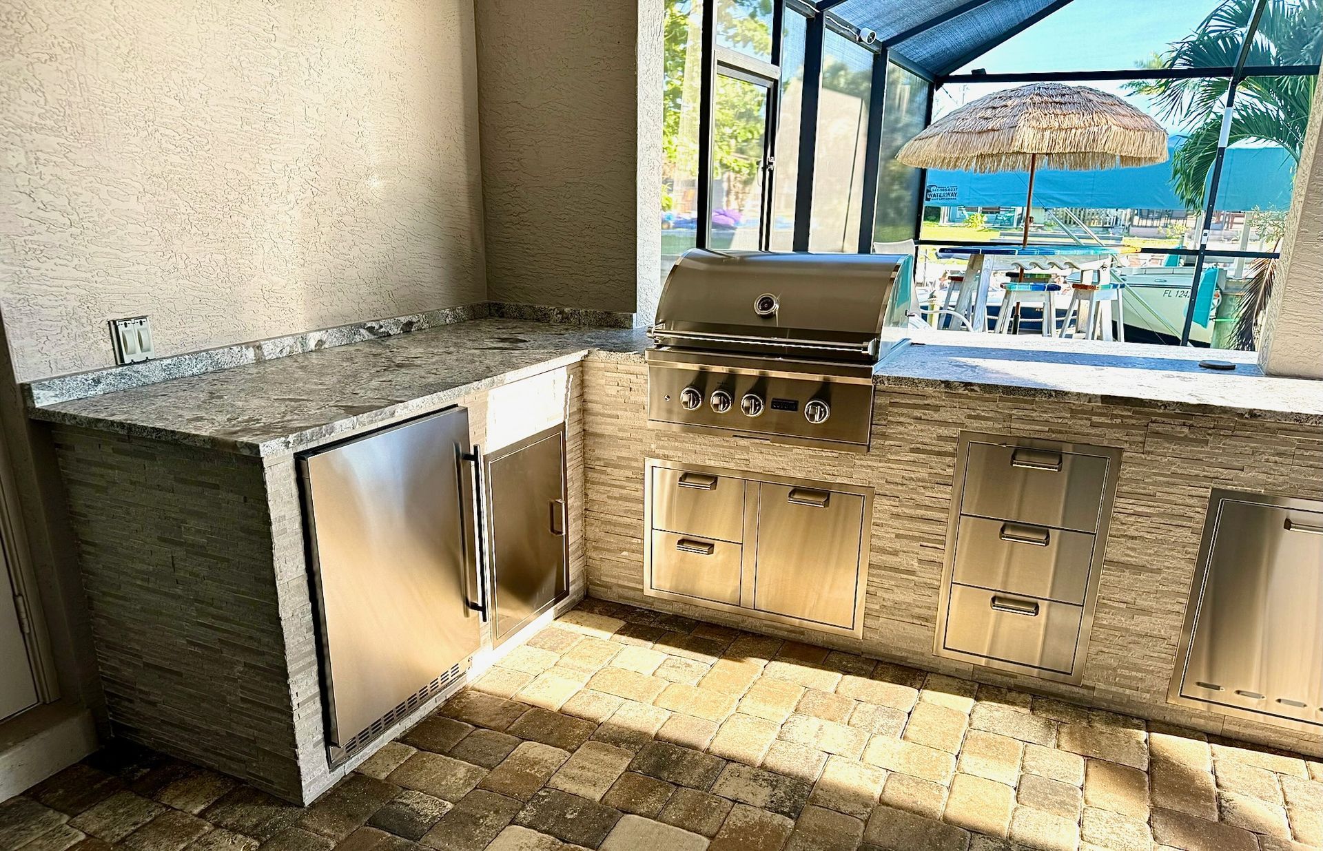 A kitchen with a grill and a window overlooking a pool.
