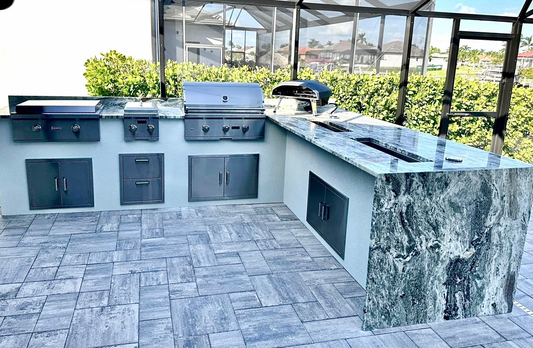 A large outdoor kitchen with a grill, sink, and cabinets.