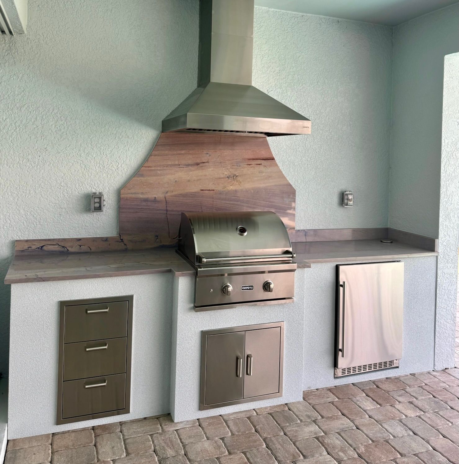 A kitchen with a grill and a hood above it.