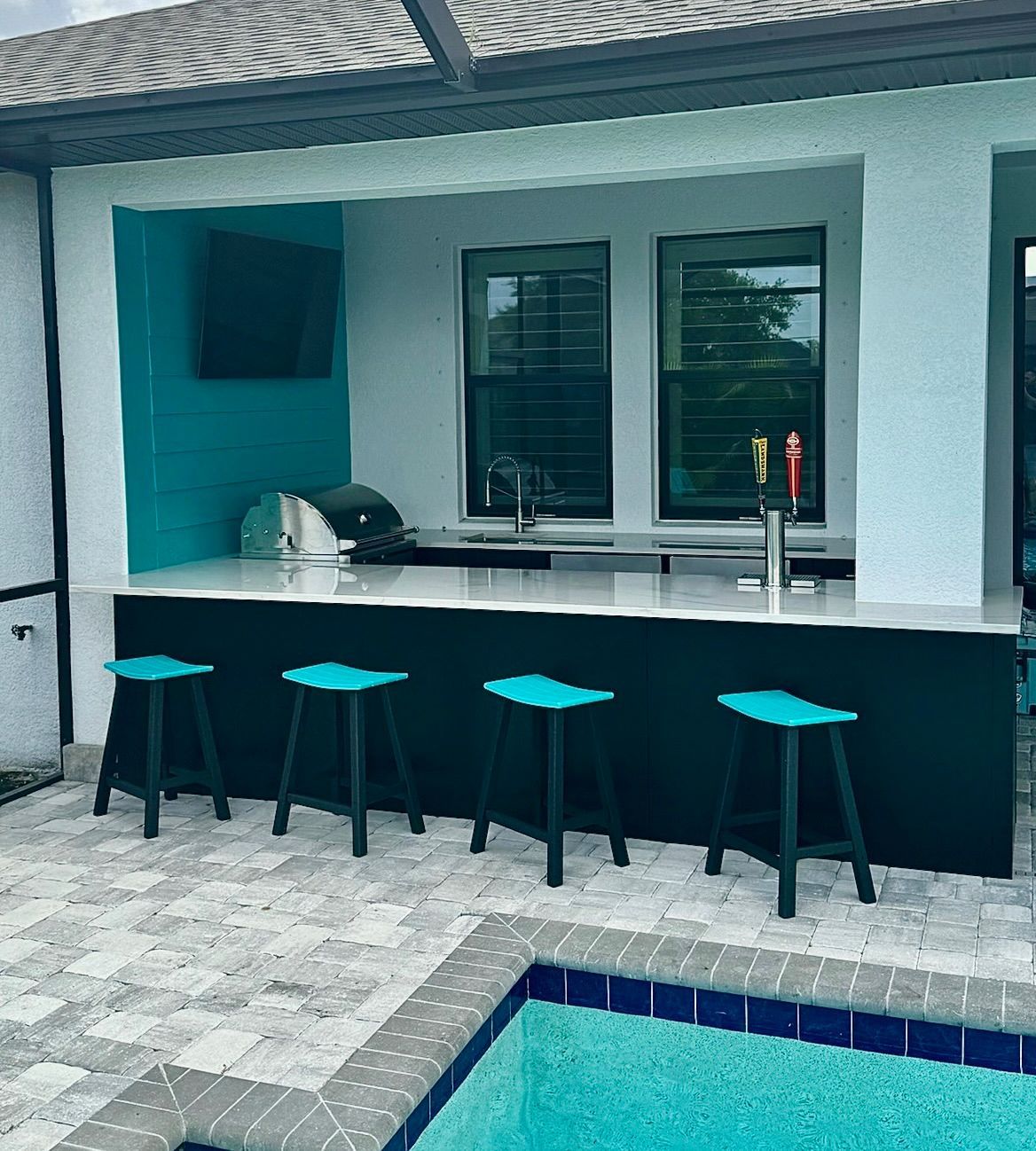 A patio with a bar and stools next to a pool.