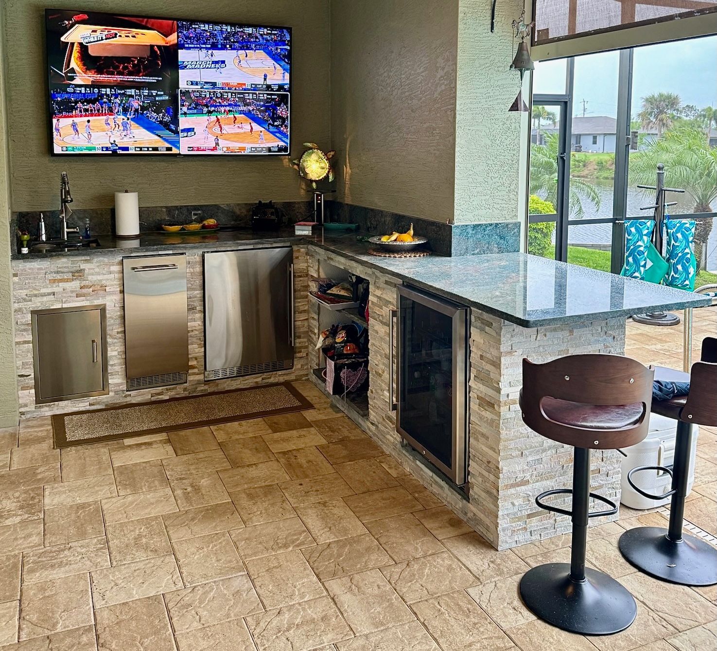 A kitchen with two bar stools and a television on the wall.