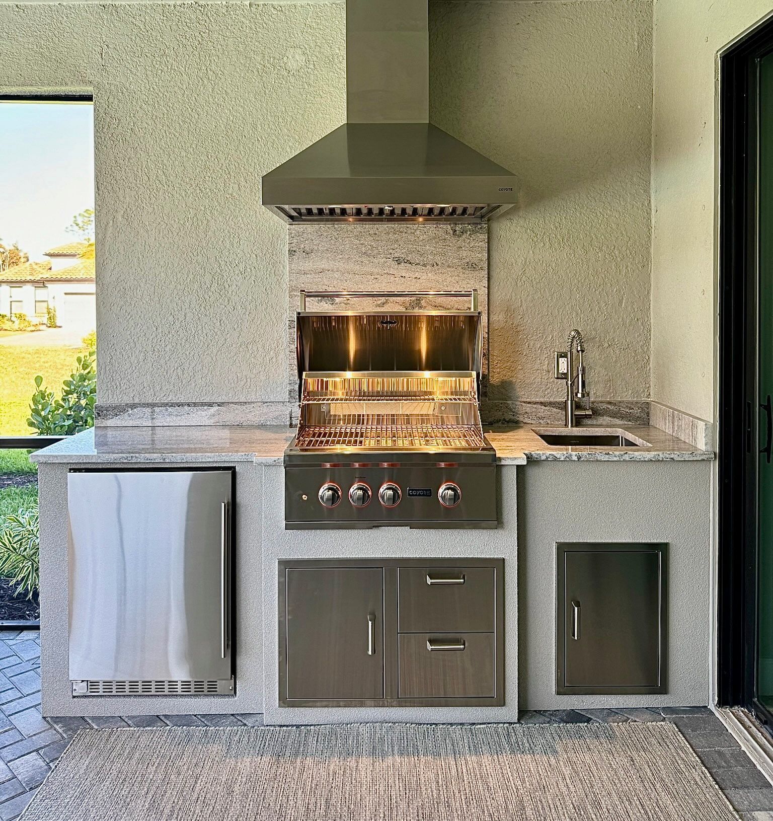 An outdoor kitchen with a grill and a sink.