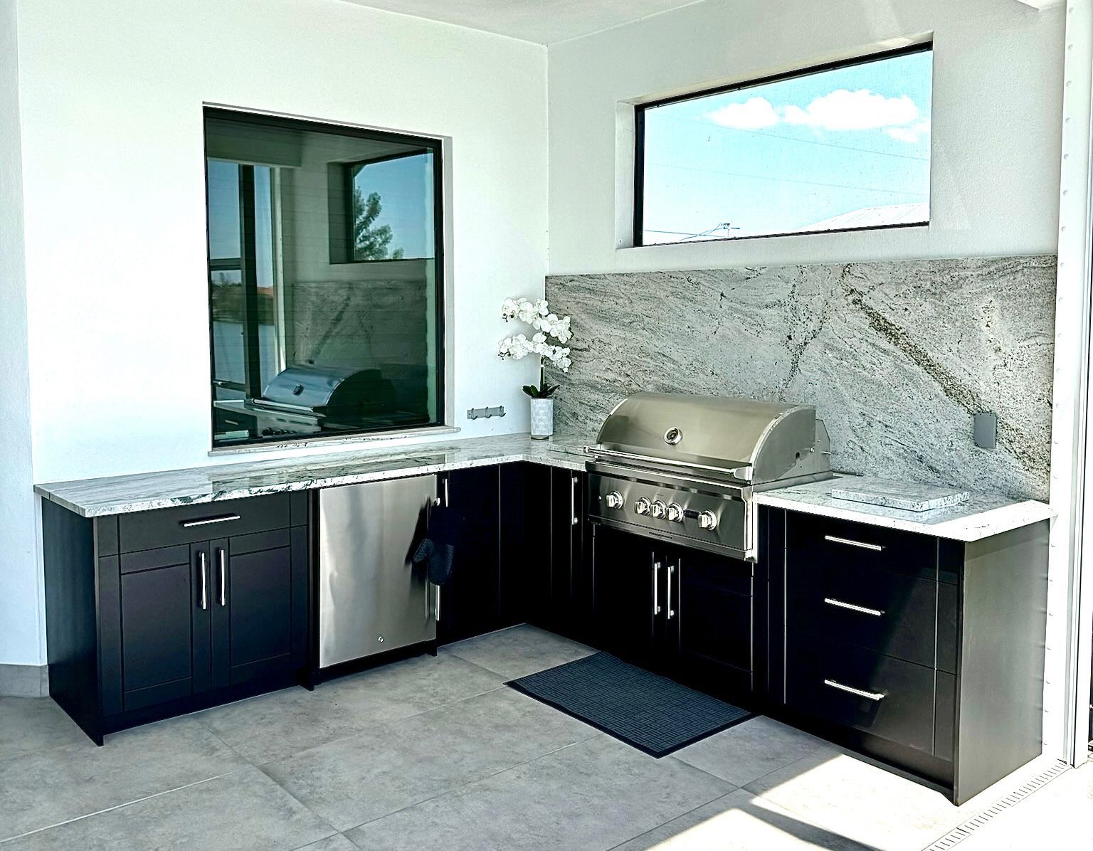 A kitchen with black cabinets and a grill and a window.