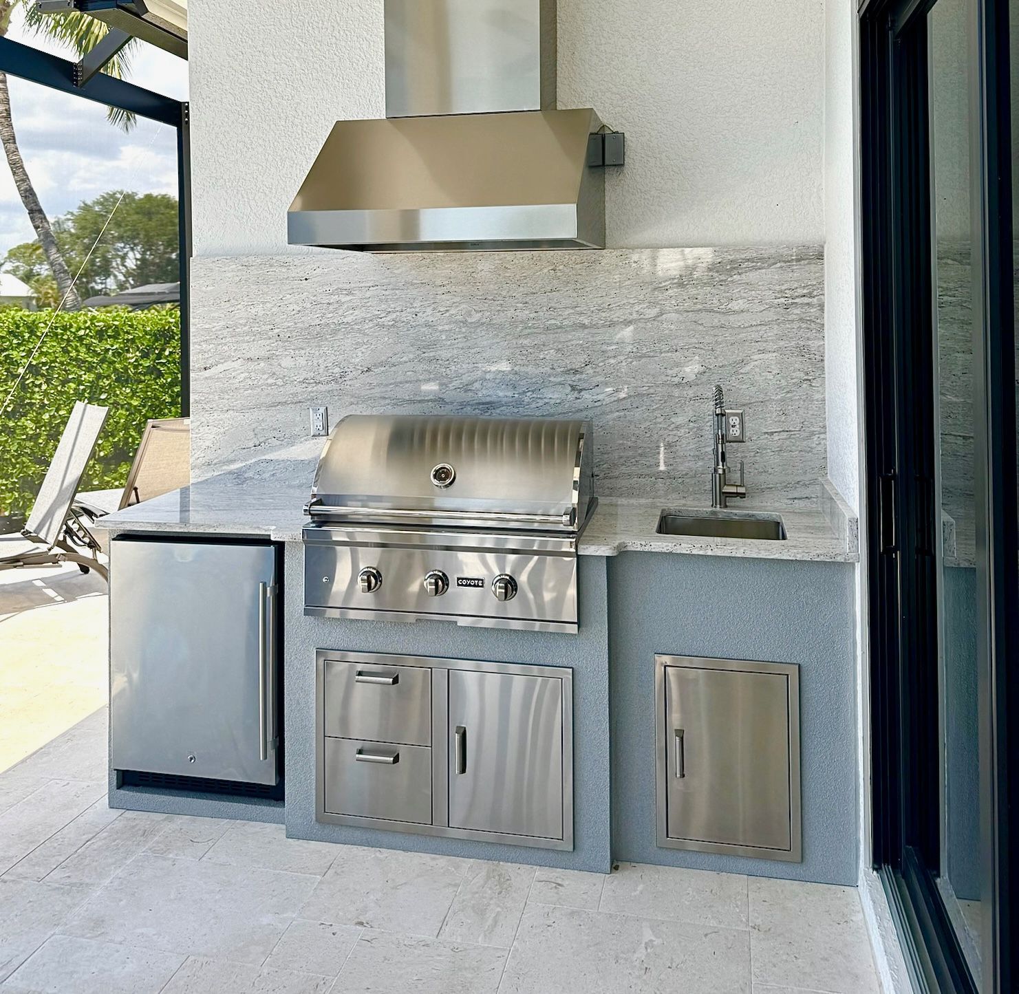 An outdoor kitchen with a stainless steel grill and sink.