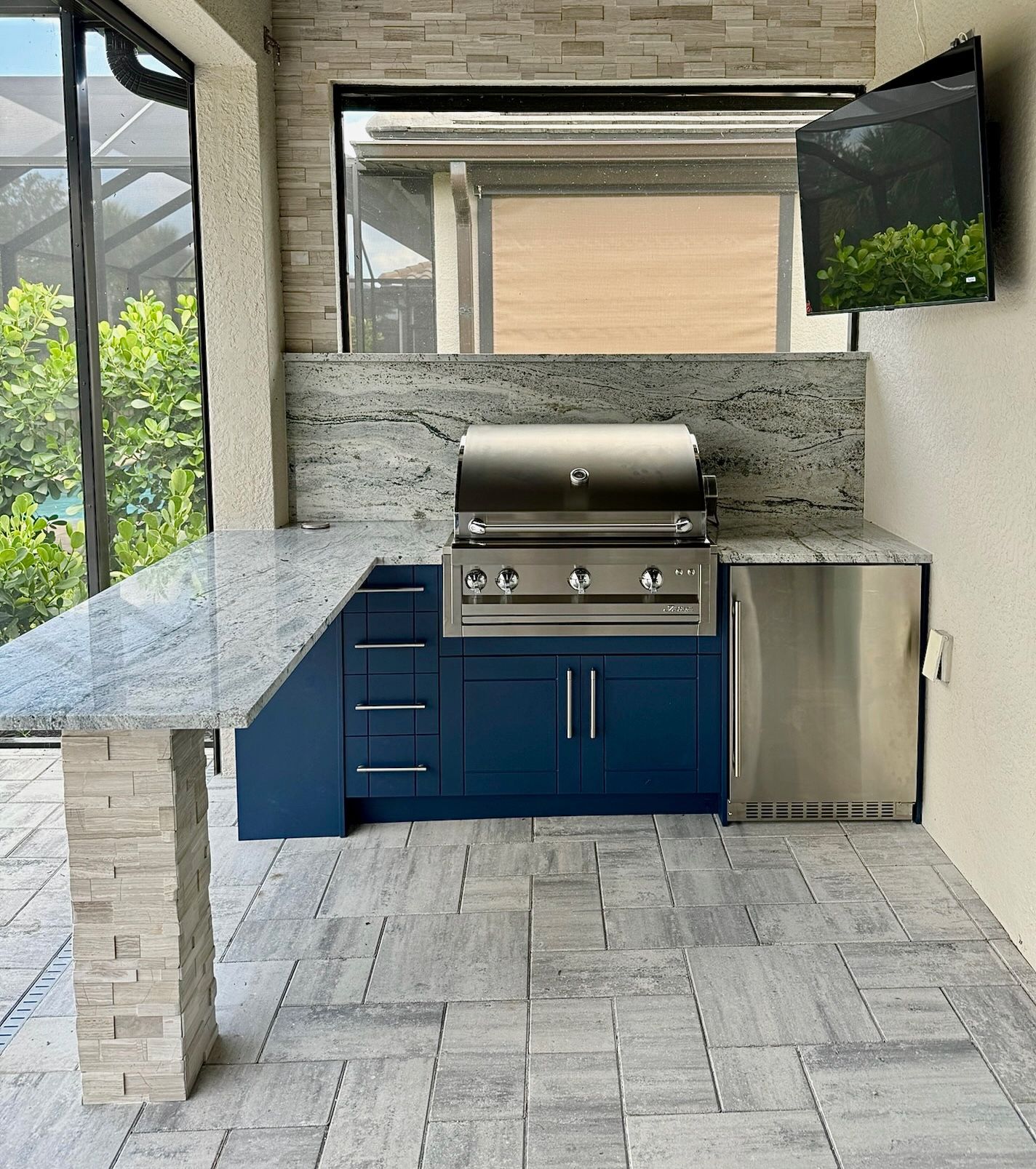 A kitchen with blue cabinets and a stainless steel grill.
