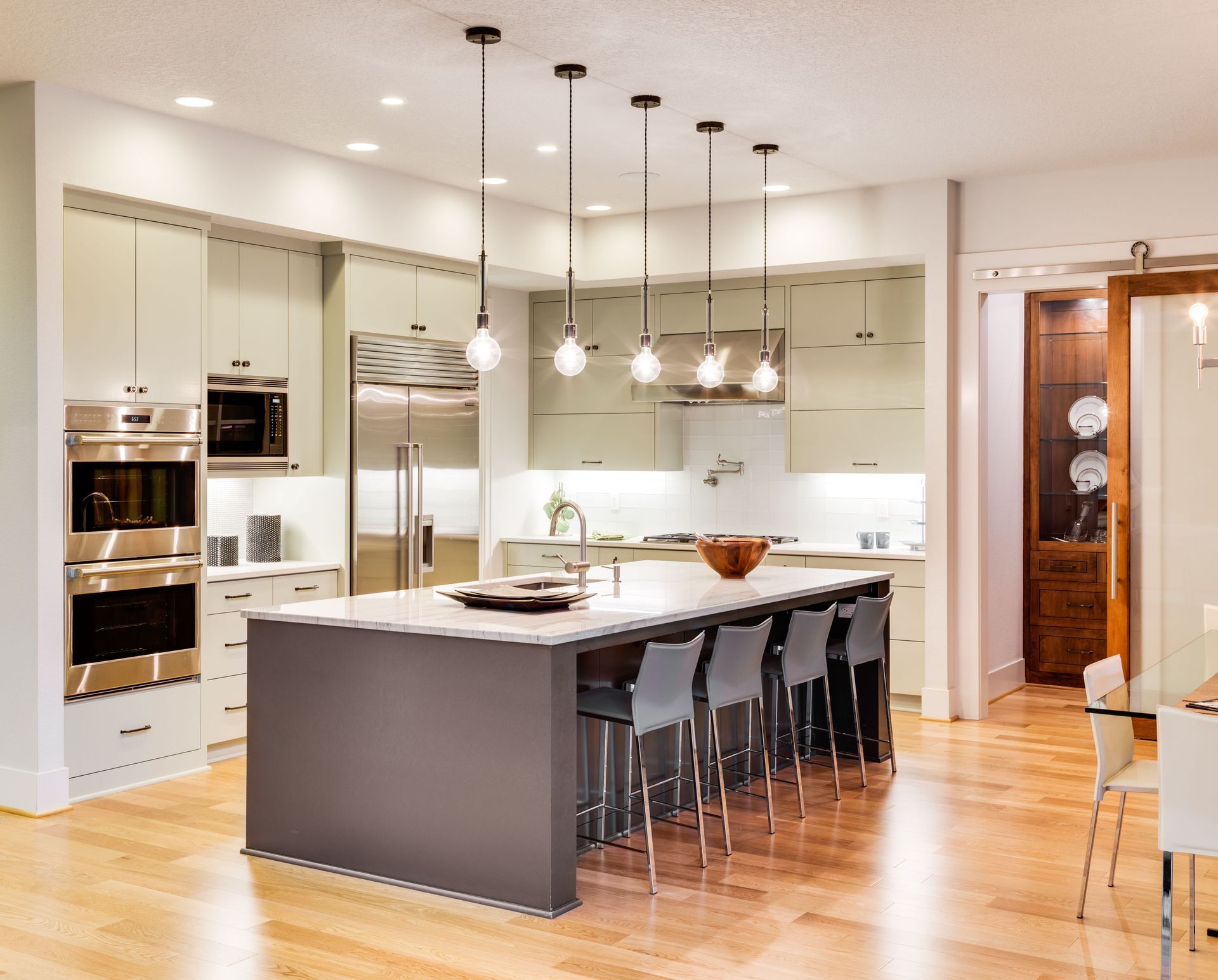 Modern kitchen with a large island, pendant lights, stainless appliances, and hardwood floors