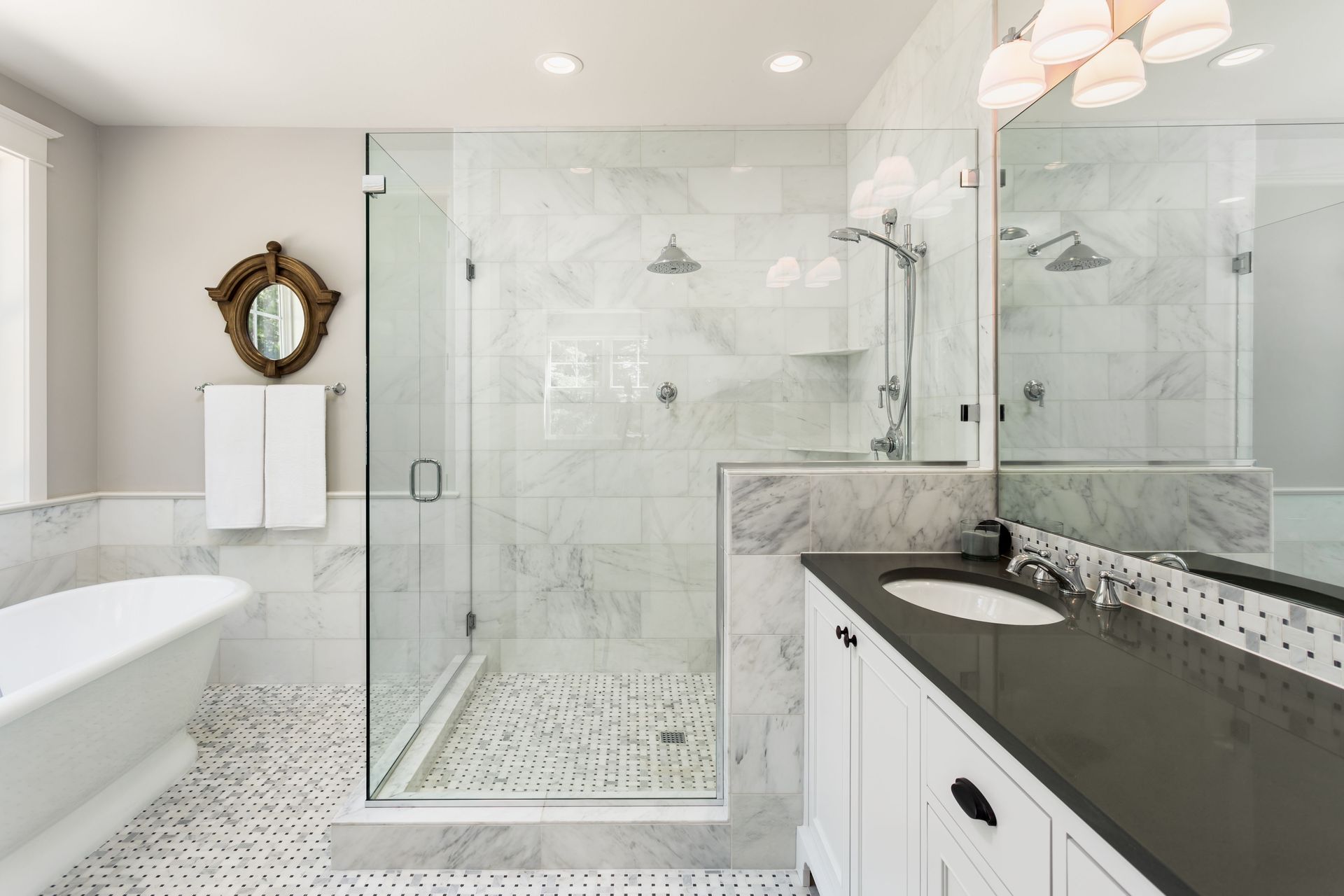Bright bathroom with glass walk-in shower, freestanding tub, and white vanity with granite countertop.