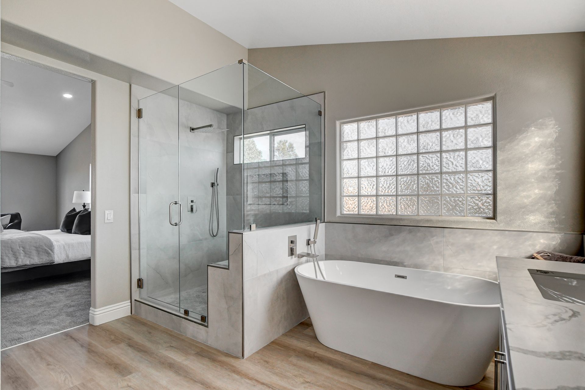 Modern bathroom with glass shower, freestanding tub, and a window.