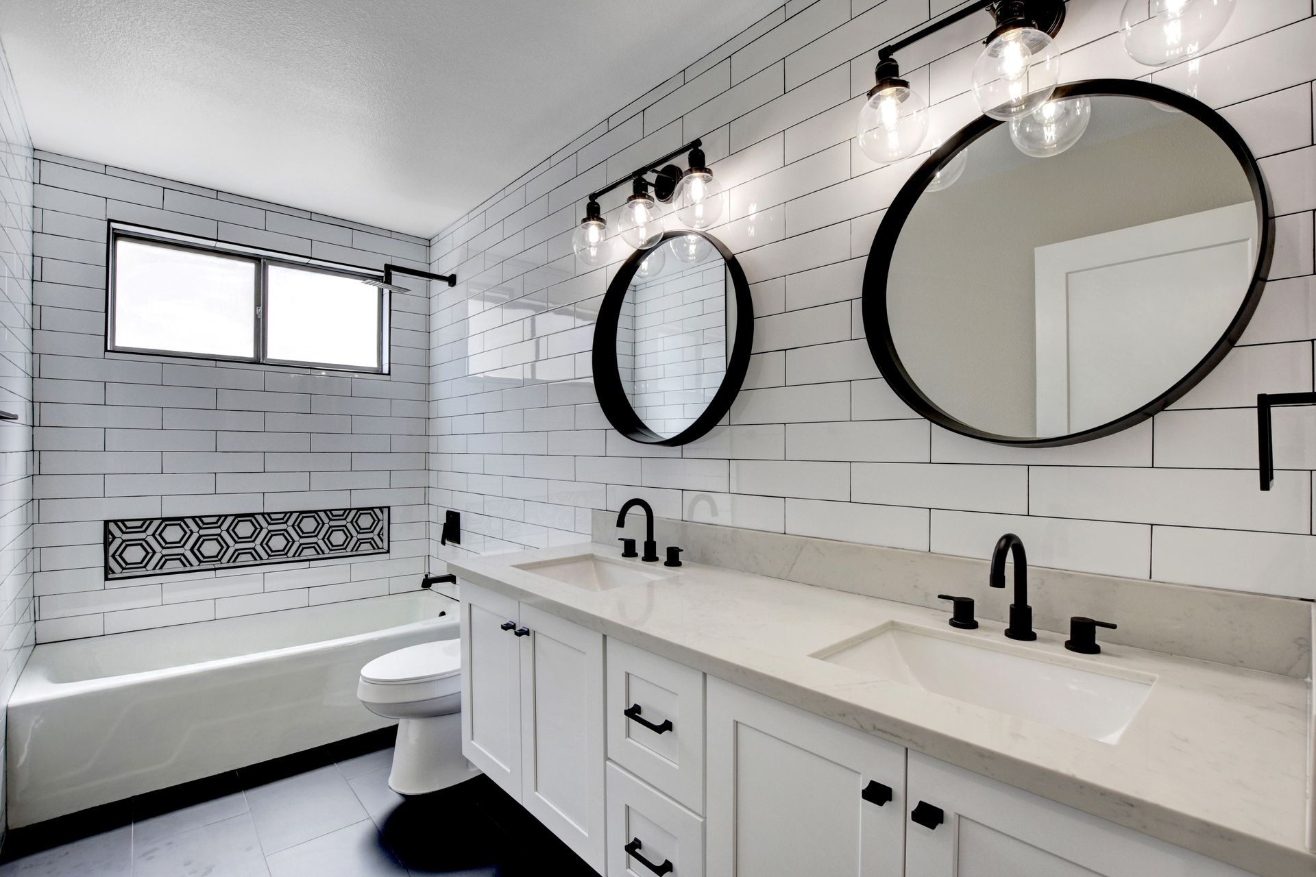 Modern bathroom with white subway tile, black accents, and double sinks.