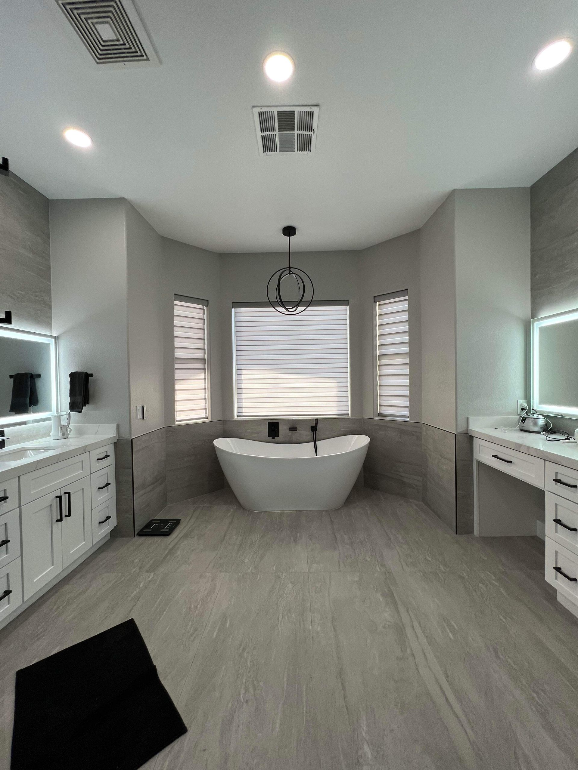 Spacious bathroom with a freestanding tub, dual vanities, and light gray tile flooring.